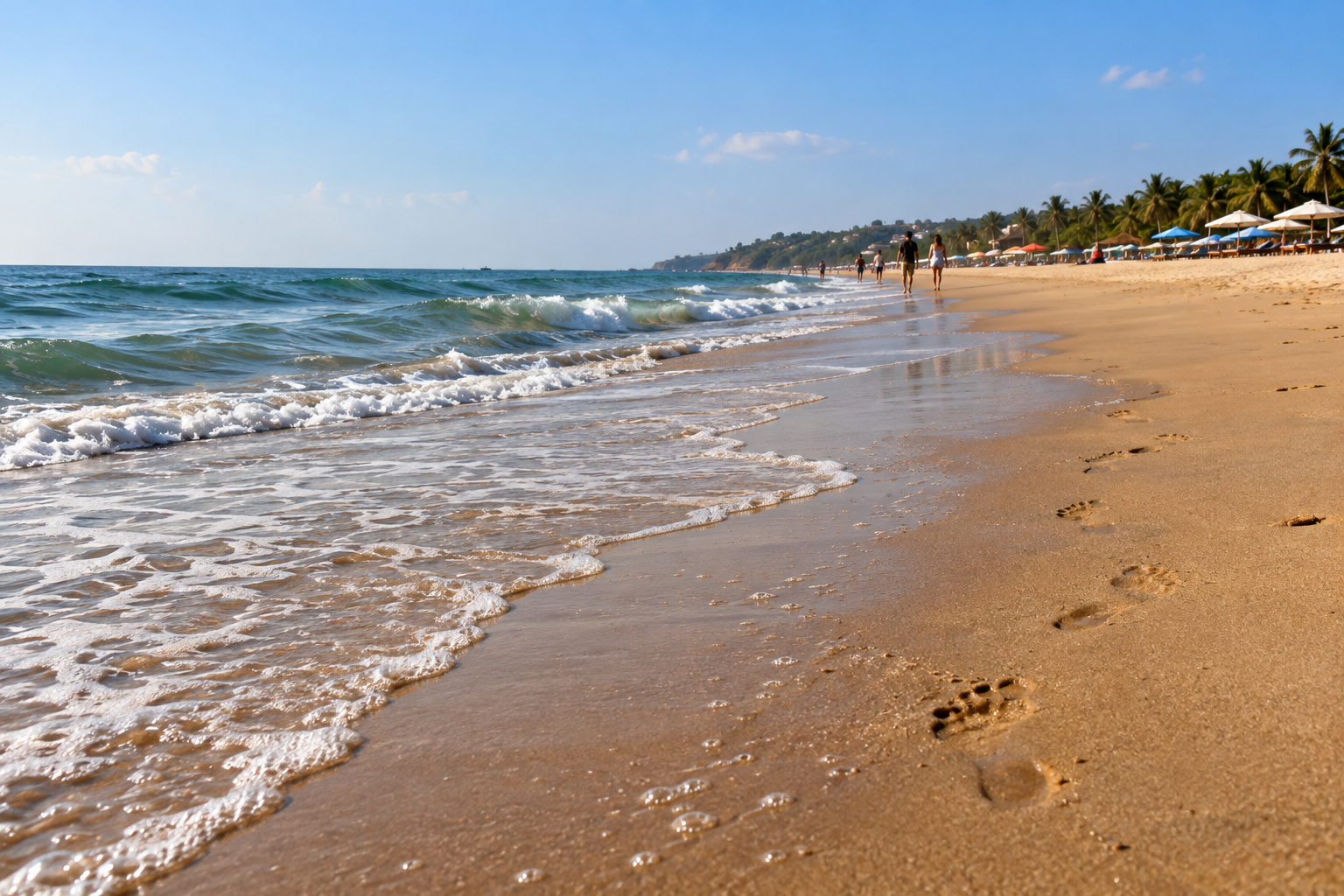 Footprints beside gentle surf on the sandy shoreline of Candolim beach